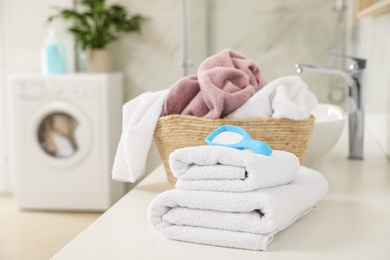 Photo of Clean towels and detergent powder on countertop in bathroom