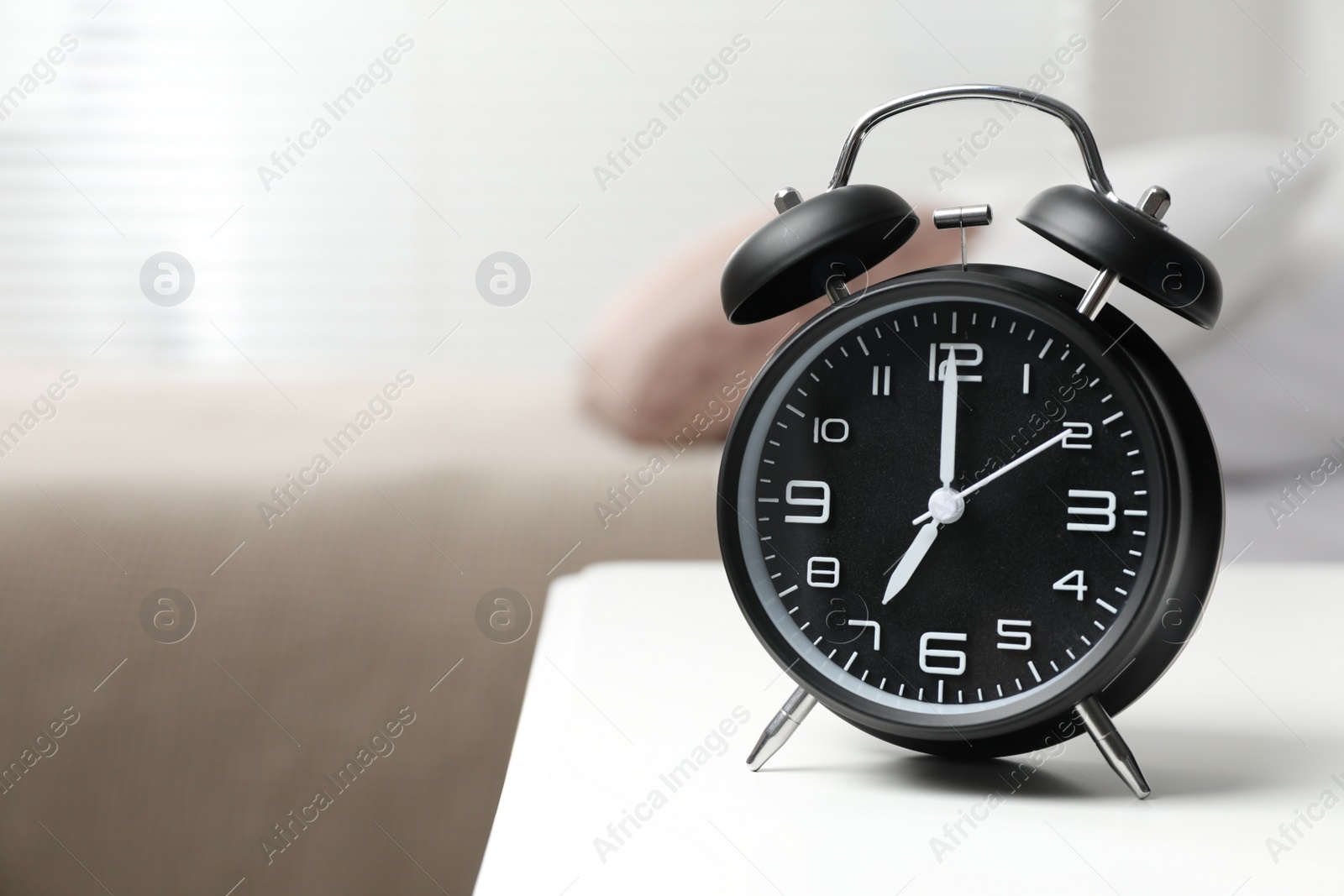 Photo of Black alarm clock on white wooden nightstand in bedroom, space for text