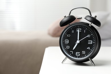 Photo of Black alarm clock on white wooden nightstand in bedroom, space for text