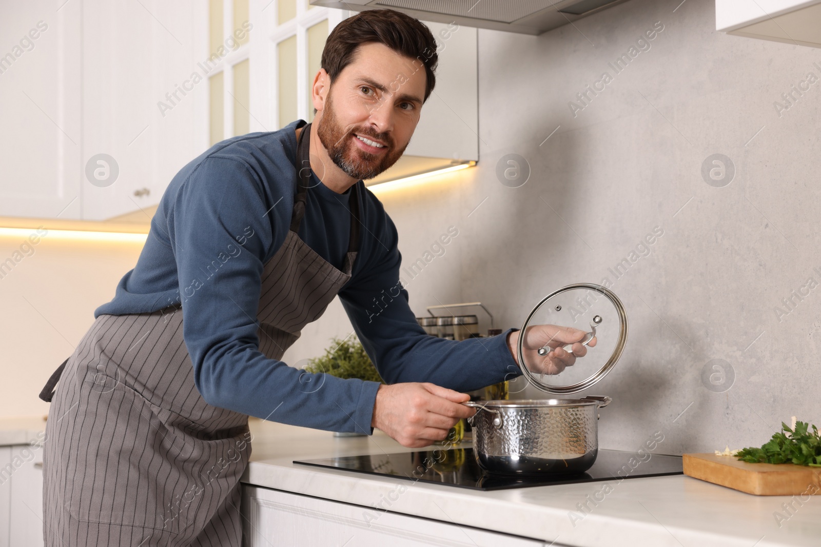 Photo of Man cooking soup on cooktop in kitchen