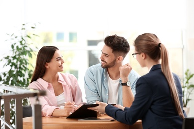 Photo of Female insurance agent working with young couple in office