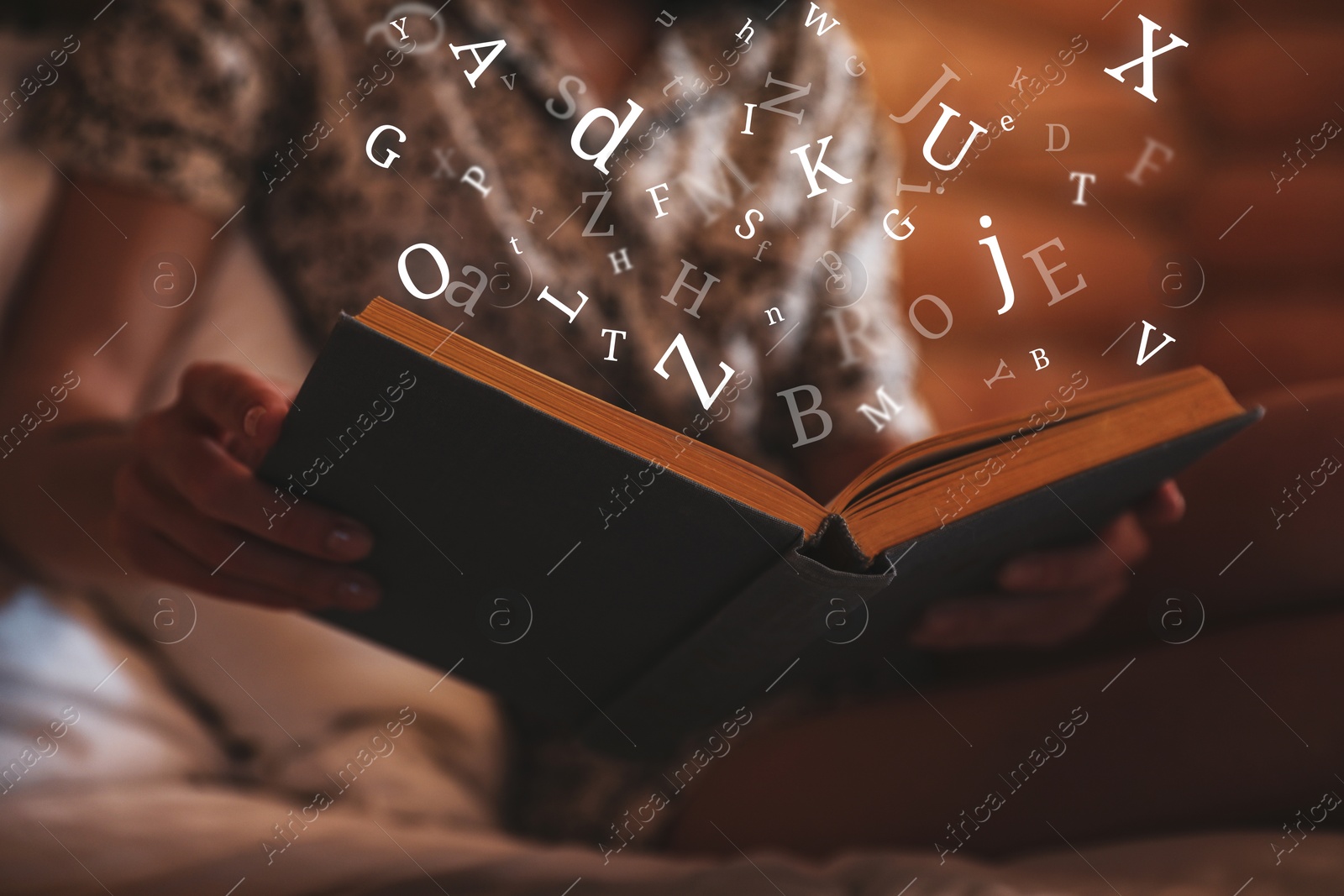 Image of Woman reading book with letters flying over it on bed at home, closeup