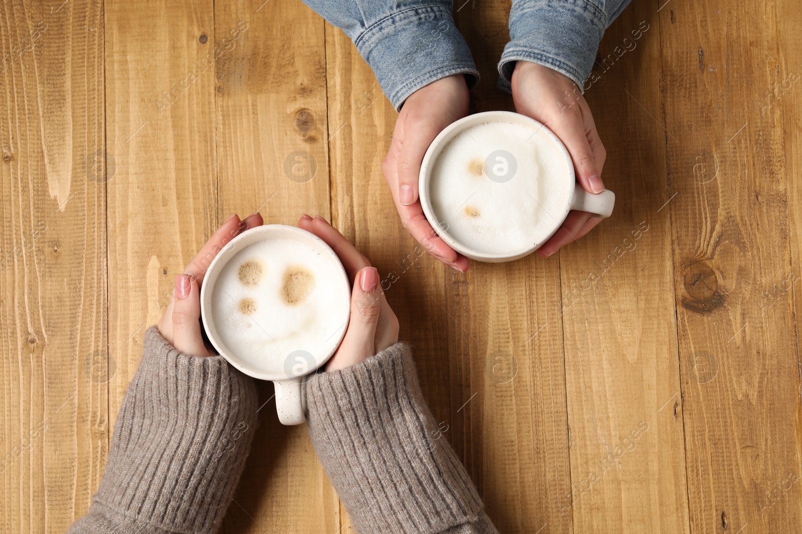 Photo of Women having coffee break at wooden table, top view