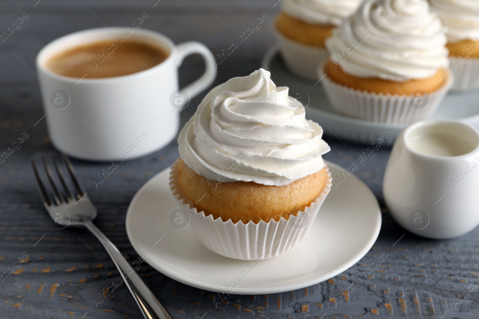 Photo of Delicious cupcake with cream on grey wooden table, closeup