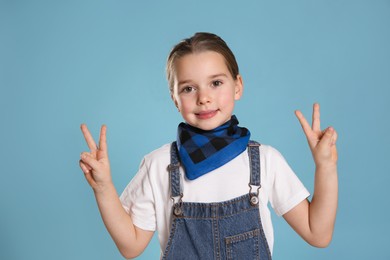 Photo of Cute little girl wearing stylish bandana on turquoise background