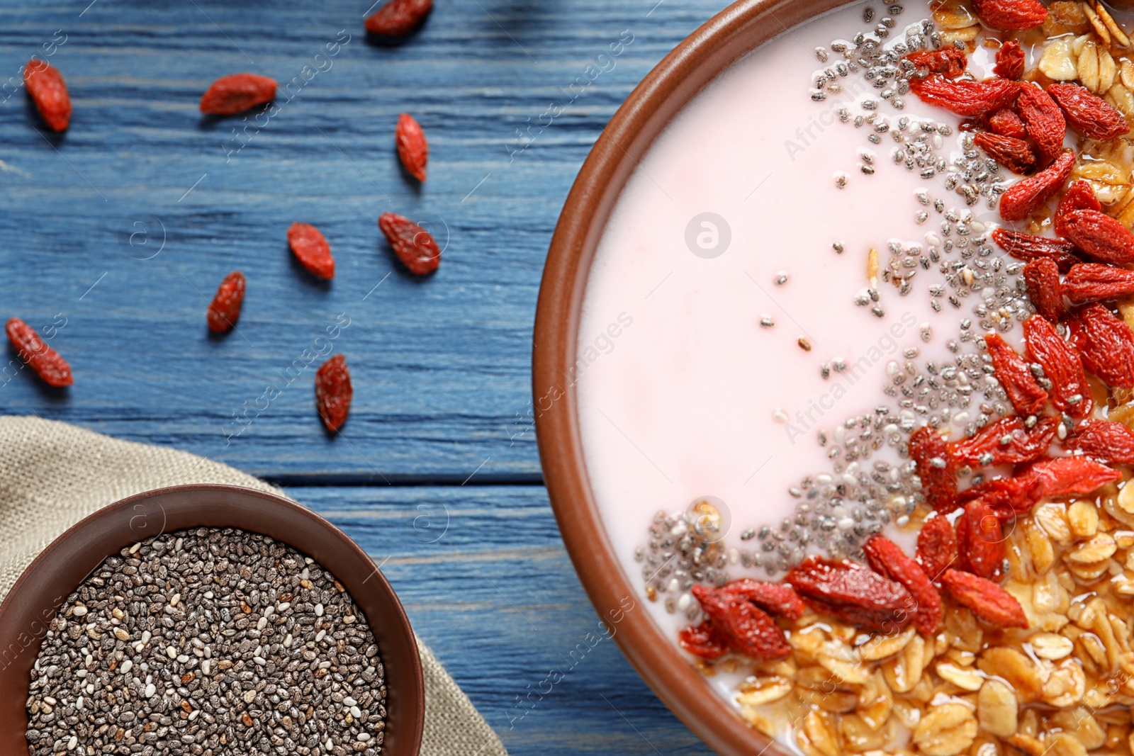 Photo of Smoothie bowl with goji berries on blue wooden table, closeup