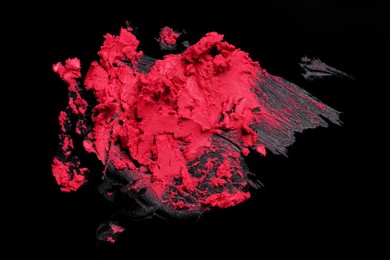 Photo of Smears of red lipstick on black background, top view