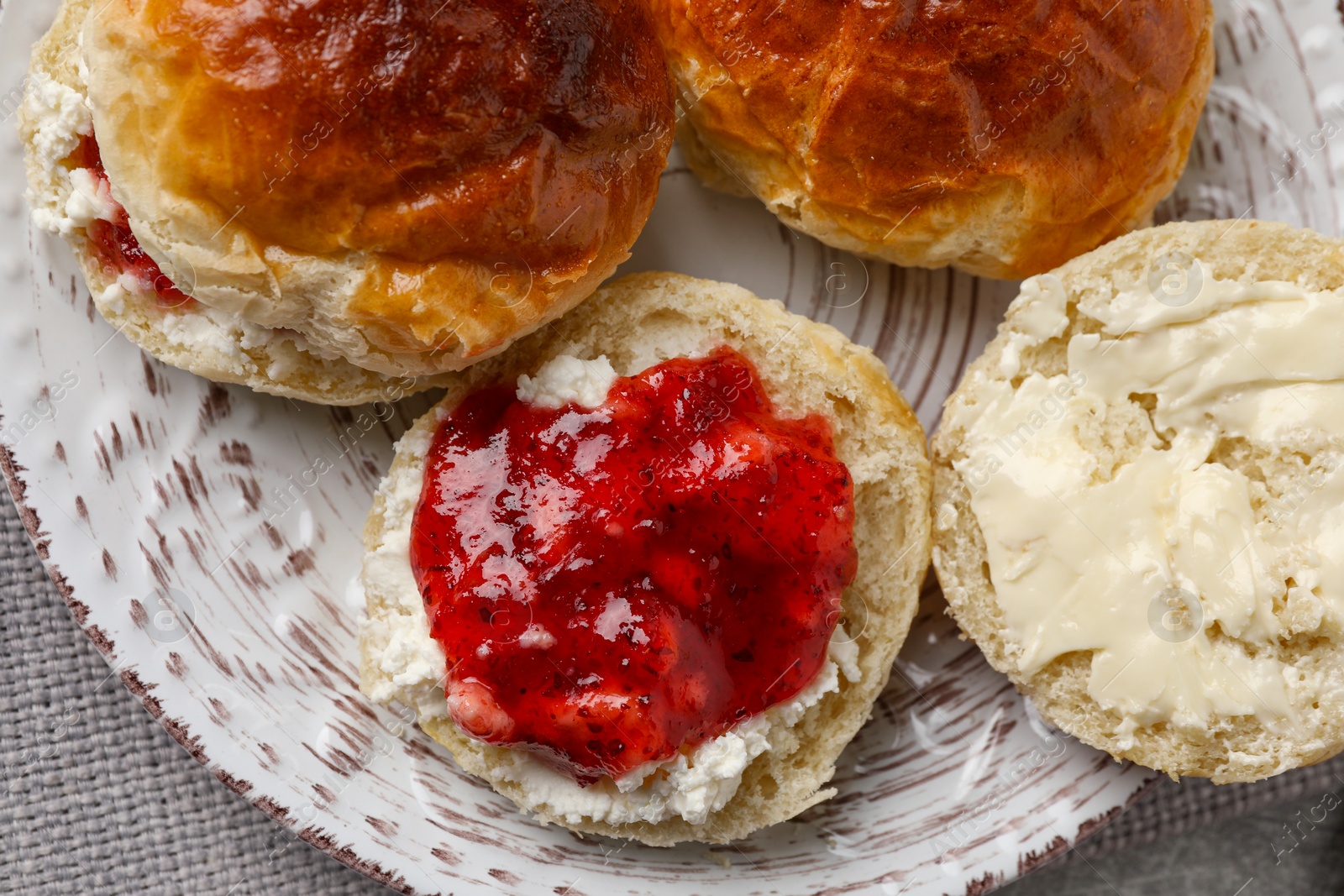 Photo of Freshly baked soda water scones with cranberry jam and butter on table, top view