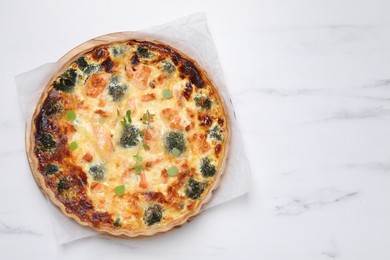 Photo of Delicious homemade quiche with salmon and broccoli on white marble table, top view. Space for text