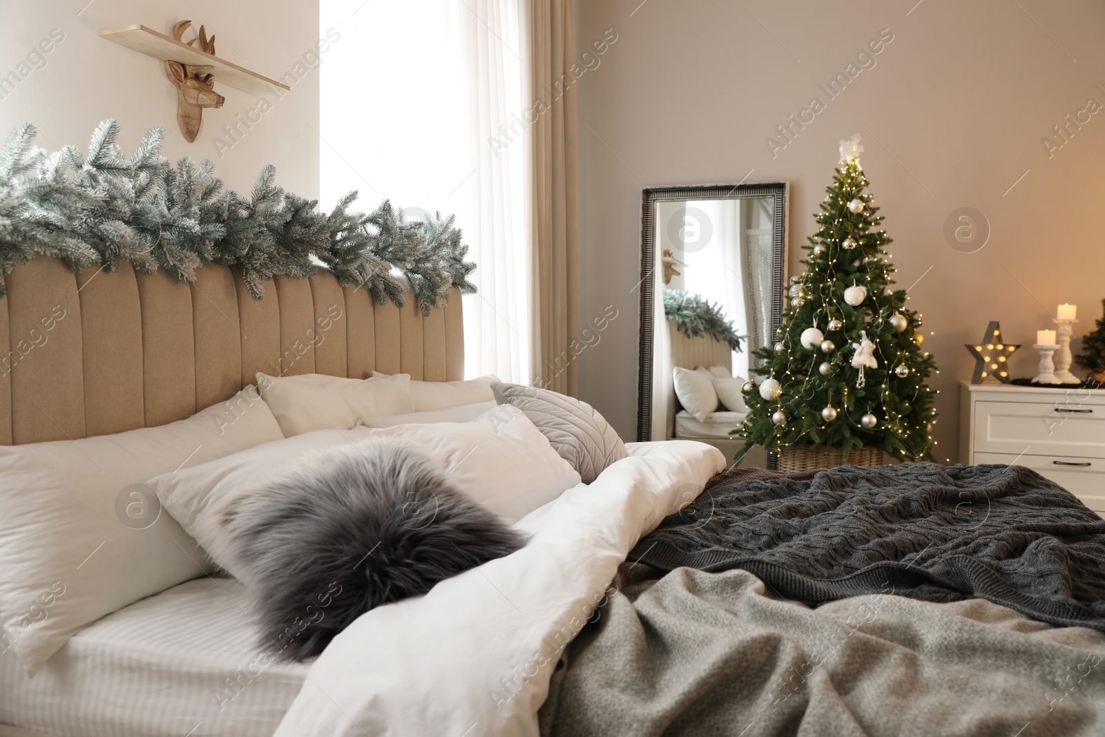 Photo of Beautiful decorated Christmas tree with fairy lights in bedroom interior