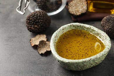Photo of Fresh truffle oil in bowl on grey table, closeup. Space for text