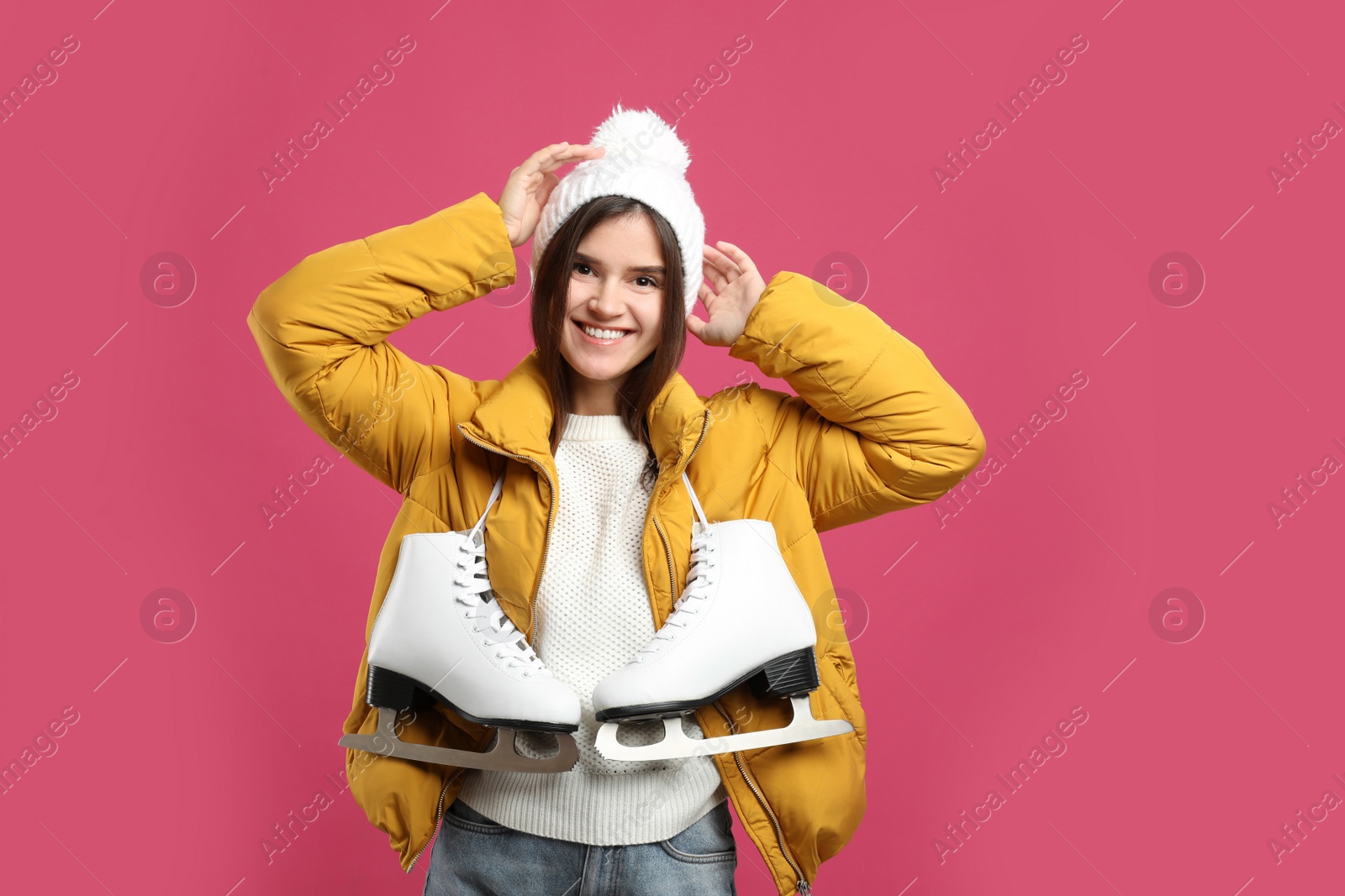 Photo of Happy woman with ice skates on pink background