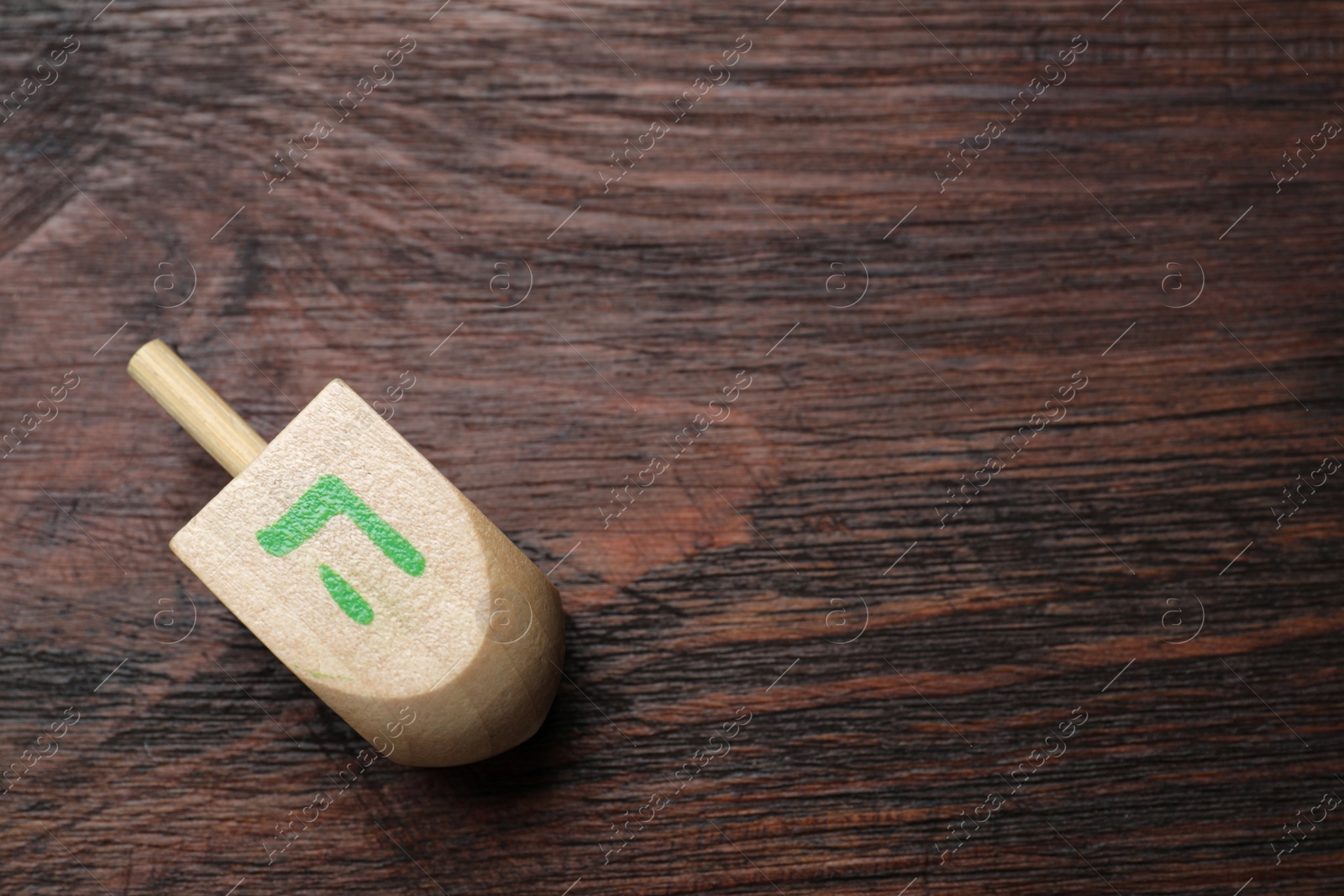 Photo of Hanukkah traditional dreidel with letter He on wooden table, top view. Space for text