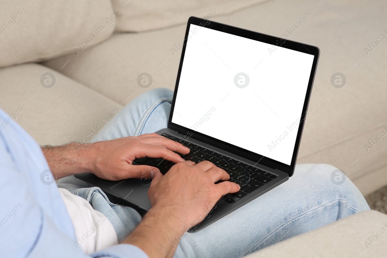 Photo of Man using laptop on sofa, closeup view