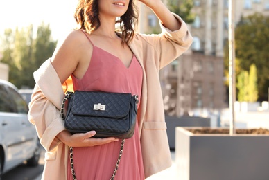 Photo of Young woman with stylish black bag on city street, closeup