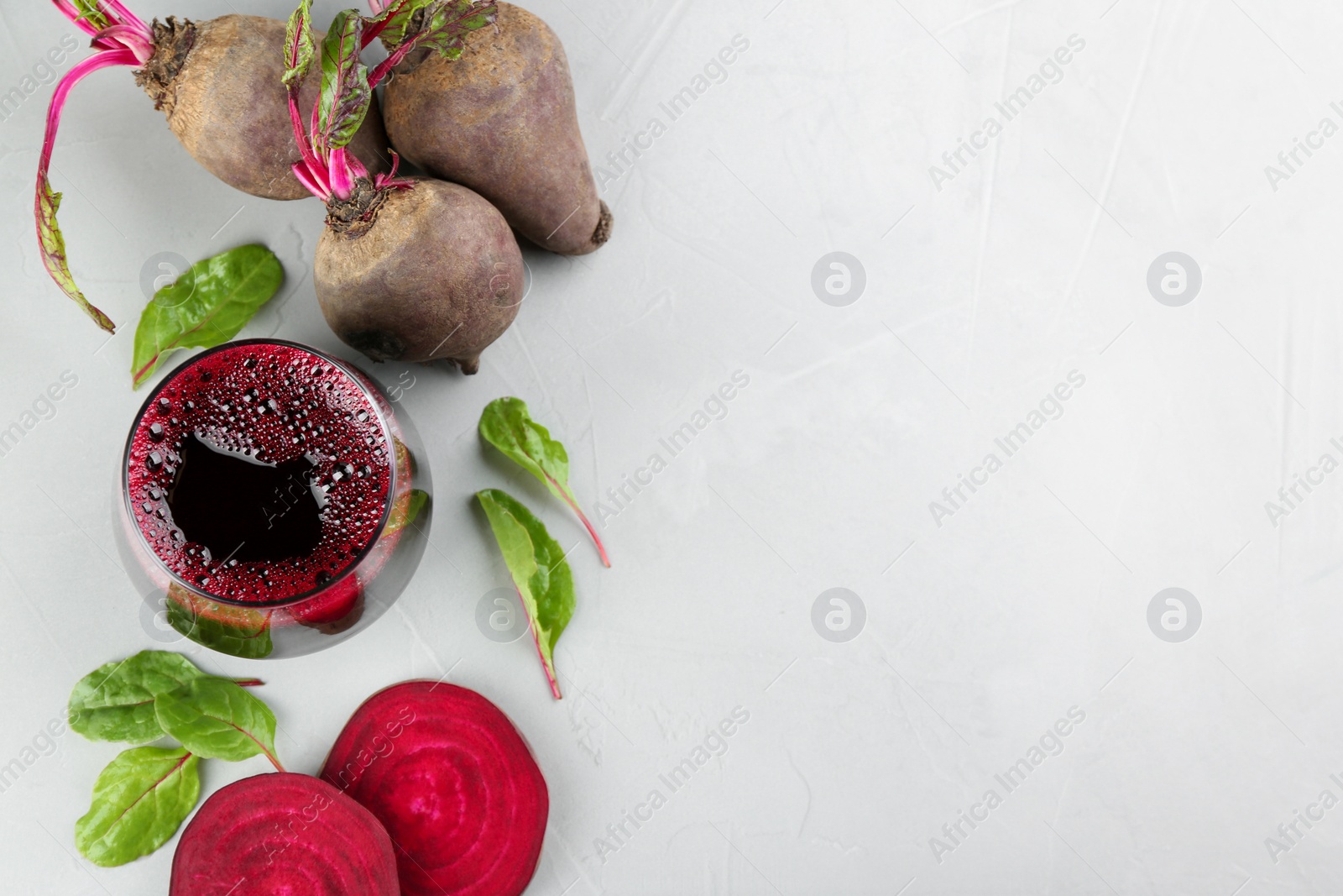 Photo of Freshly made beet juice on grey table, flat lay. Space for text