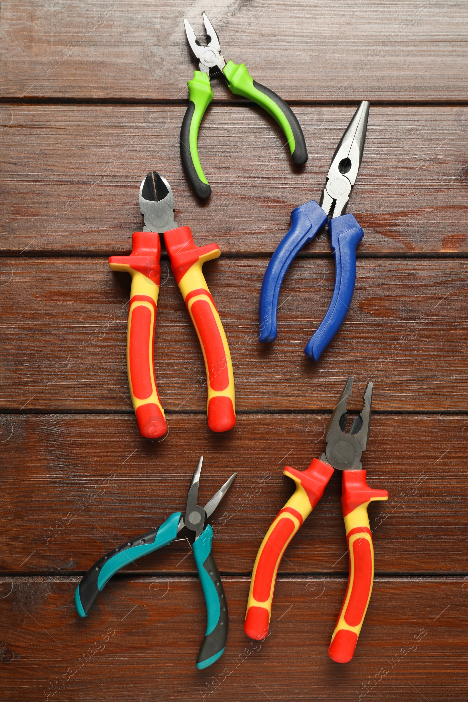Photo of Different pliers on wooden table, flat lay