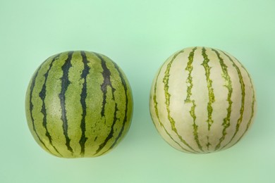 Photo of Different whole ripe watermelons on light turquoise background, flat lay