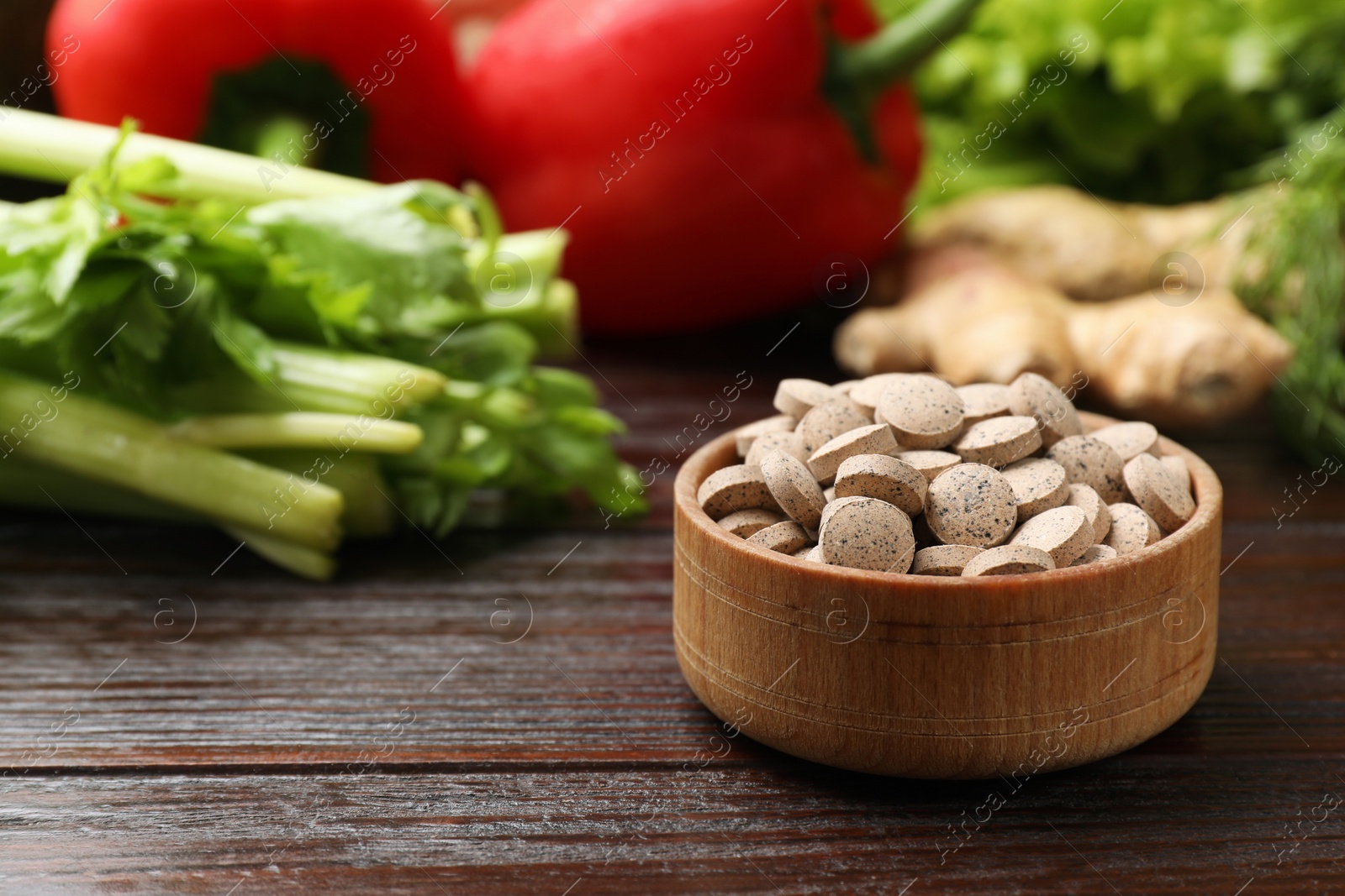 Photo of Dietary supplements. Pills in bowl and food products on wooden table, closeup