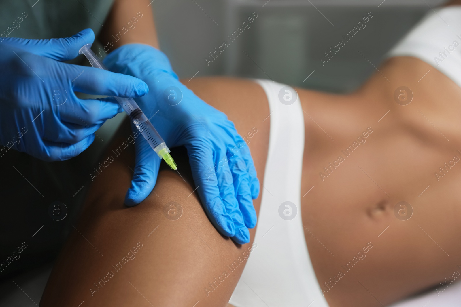 Photo of Young woman getting legs injection in salon, closeup