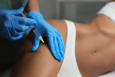 Photo of Young woman getting legs injection in salon, closeup