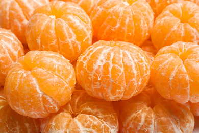 Photo of Peeled fresh ripe tangerines as background, closeup