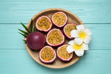 Passion fruits (maracuyas), palm leaf and flowers on light blue wooden table, top view