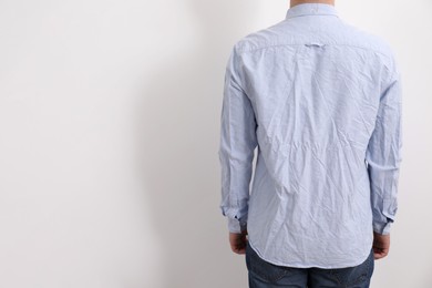 Man wearing rumpled shirt on white background, back view