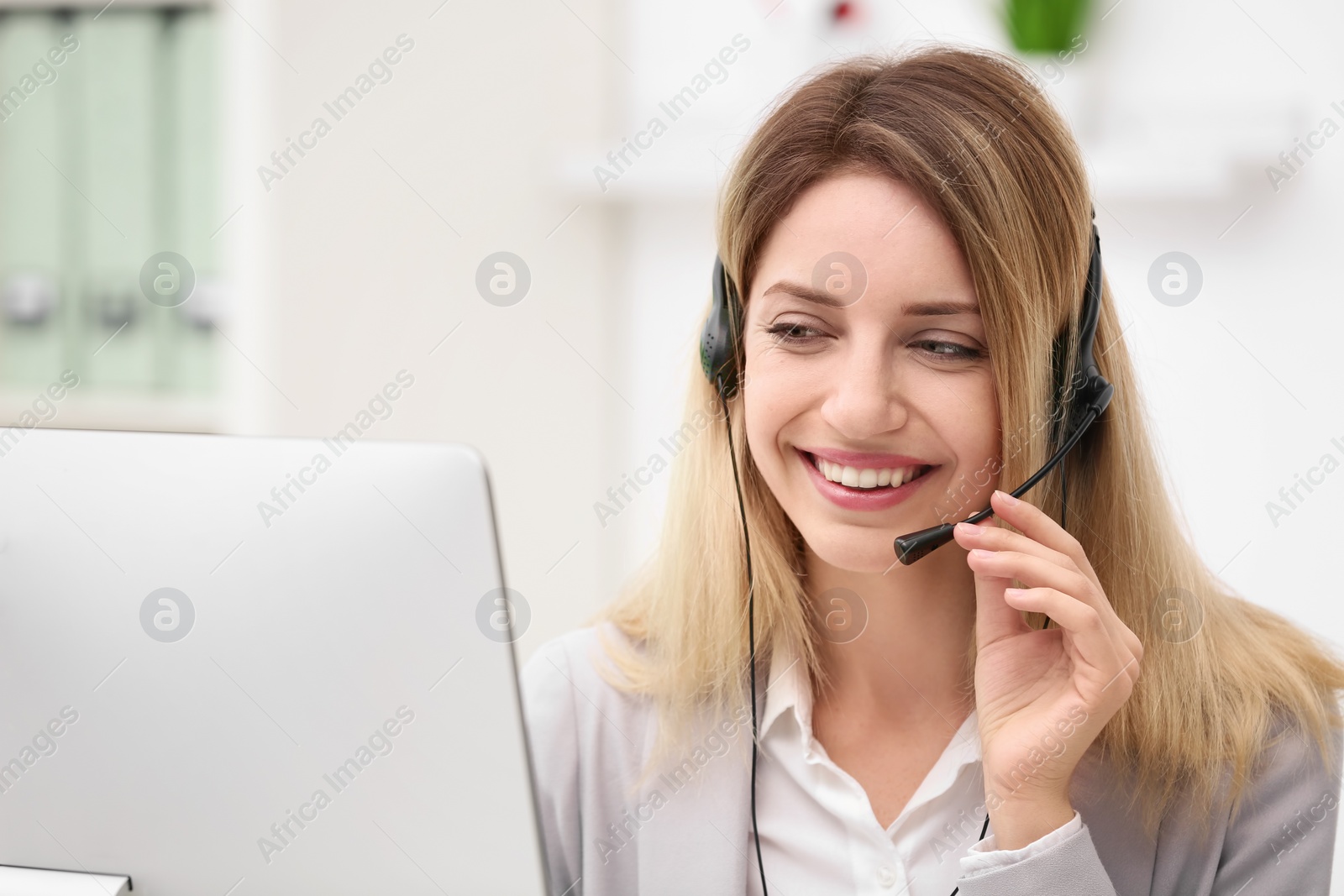 Photo of Young female receptionist with headset in office