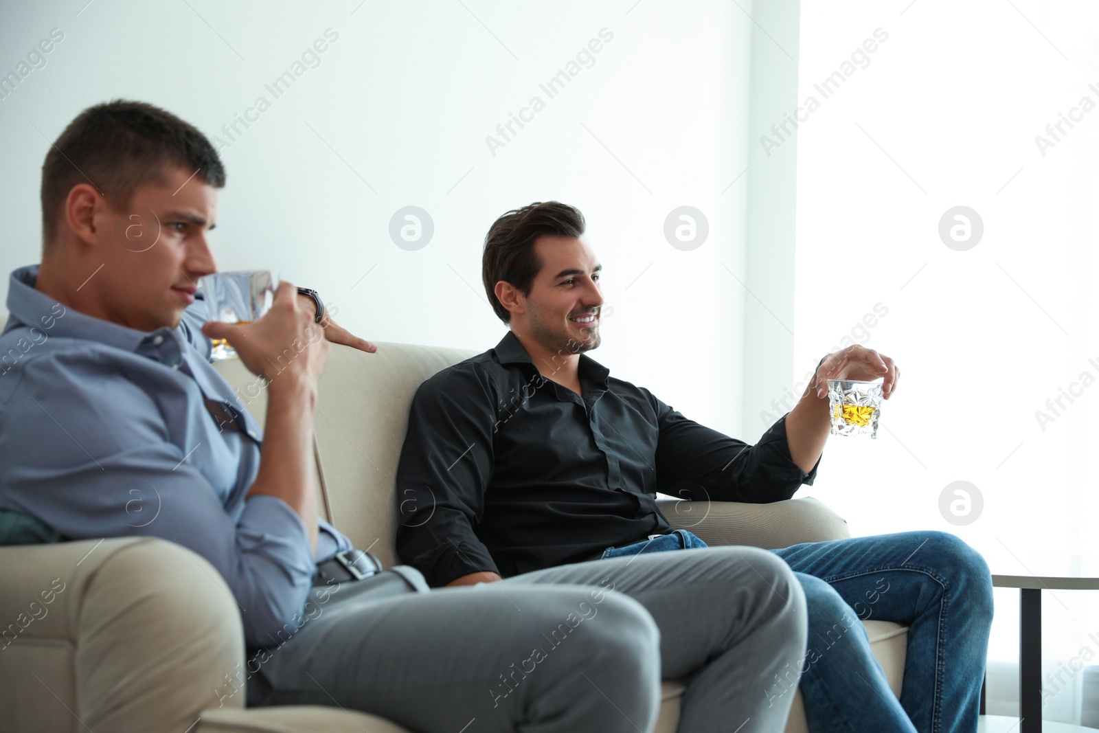 Photo of Young men drinking whiskey together at home