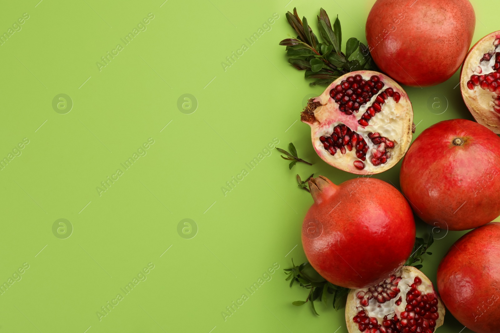 Photo of Flat lay composition with ripe pomegranates on green background. Space for text