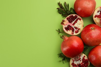 Flat lay composition with ripe pomegranates on green background. Space for text