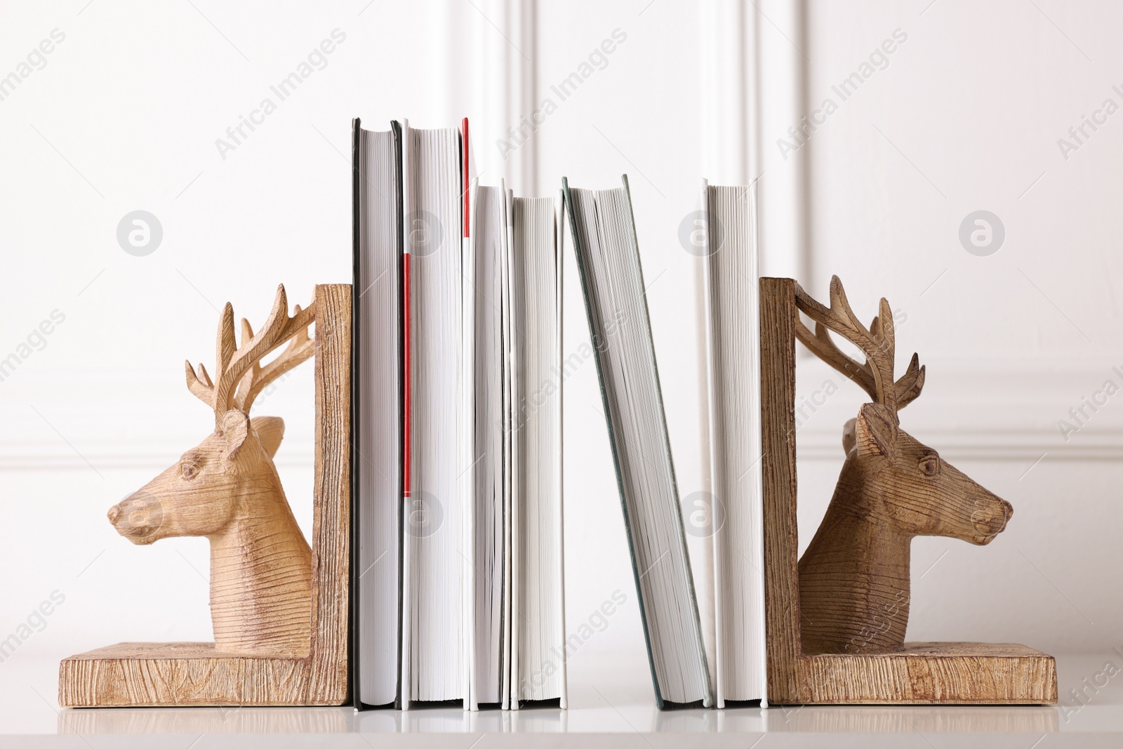 Photo of Wooden deer shaped bookends with books on table indoors