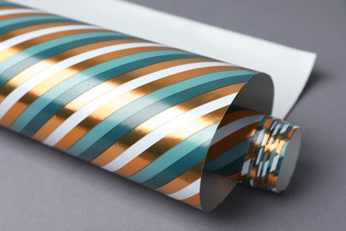 Photo of Roll of striped wrapping paper on grey background, closeup