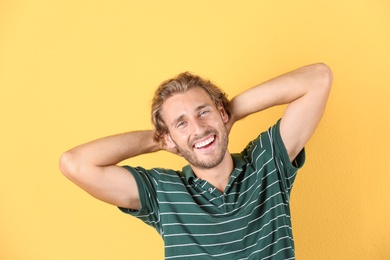 Photo of Handsome young man laughing on color background