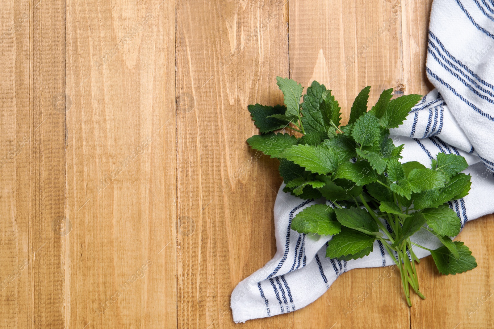 Photo of Fresh lemon balm on wooden table, top view. Space for text