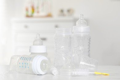 Clean baby bottles with nipples after sterilization and cleaning brush on white table indoors