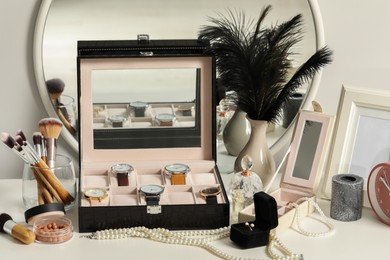Photo of Jewelry boxes with many stylish wristwatches, accessories, perfumes, makeup brushes and decor on white table