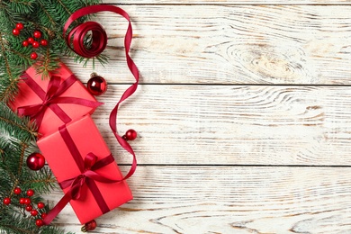 Photo of Gift boxes, Christmas balls and festive decor on white wooden table, flat lay. Space for text