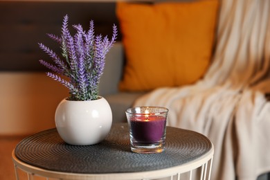 Photo of Burning candle and vase with lavender flowers on table indoors. Cosy atmosphere