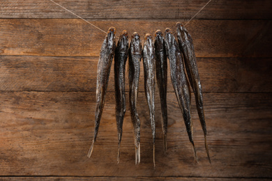 Dried fish hanging on rope against wooden background