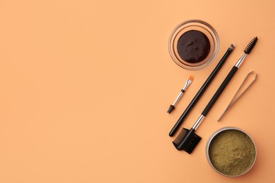 Photo of Flat lay composition with eyebrow henna and professional tools on orange background, space for text