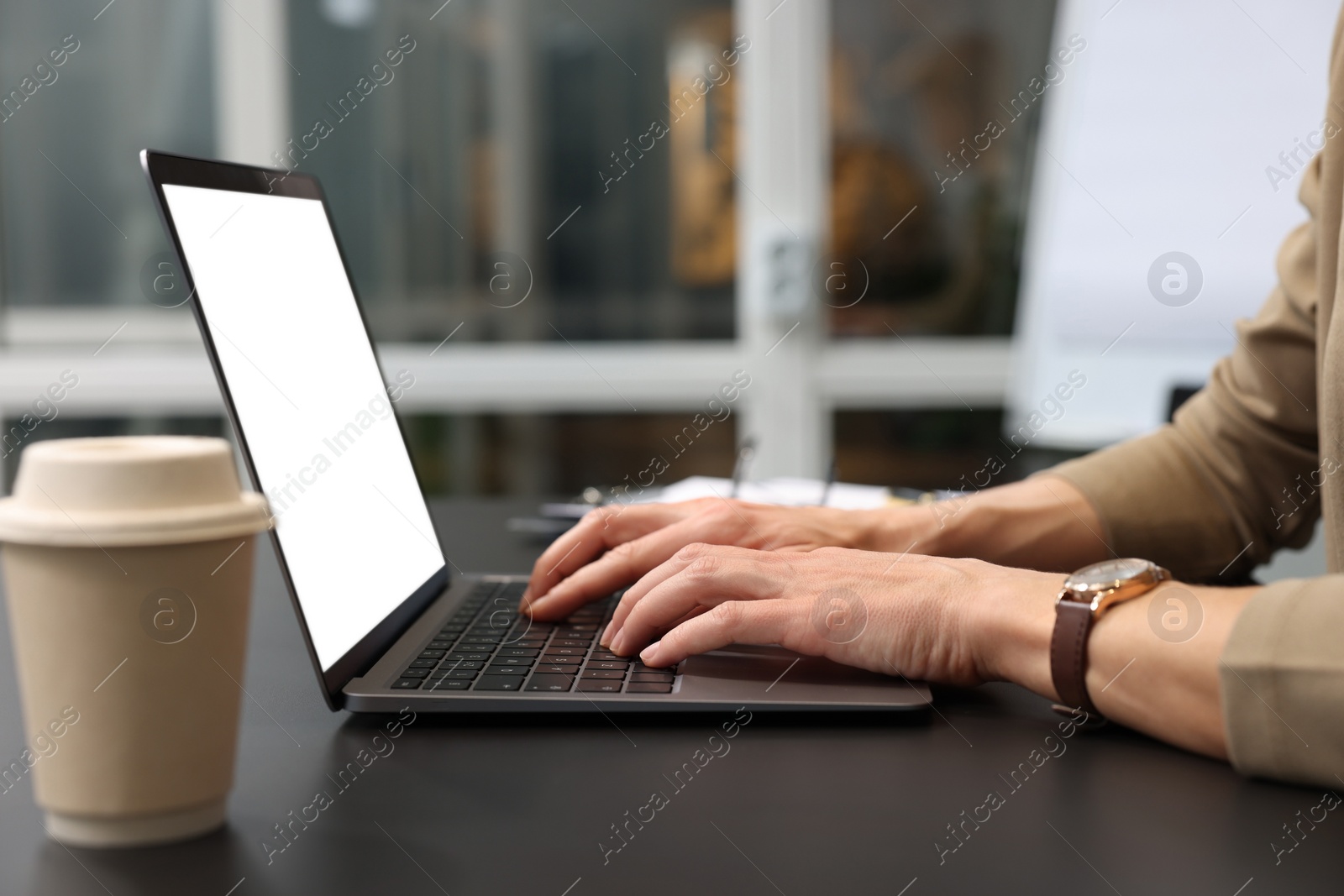 Photo of Woman working on laptop at black desk in office, closeup