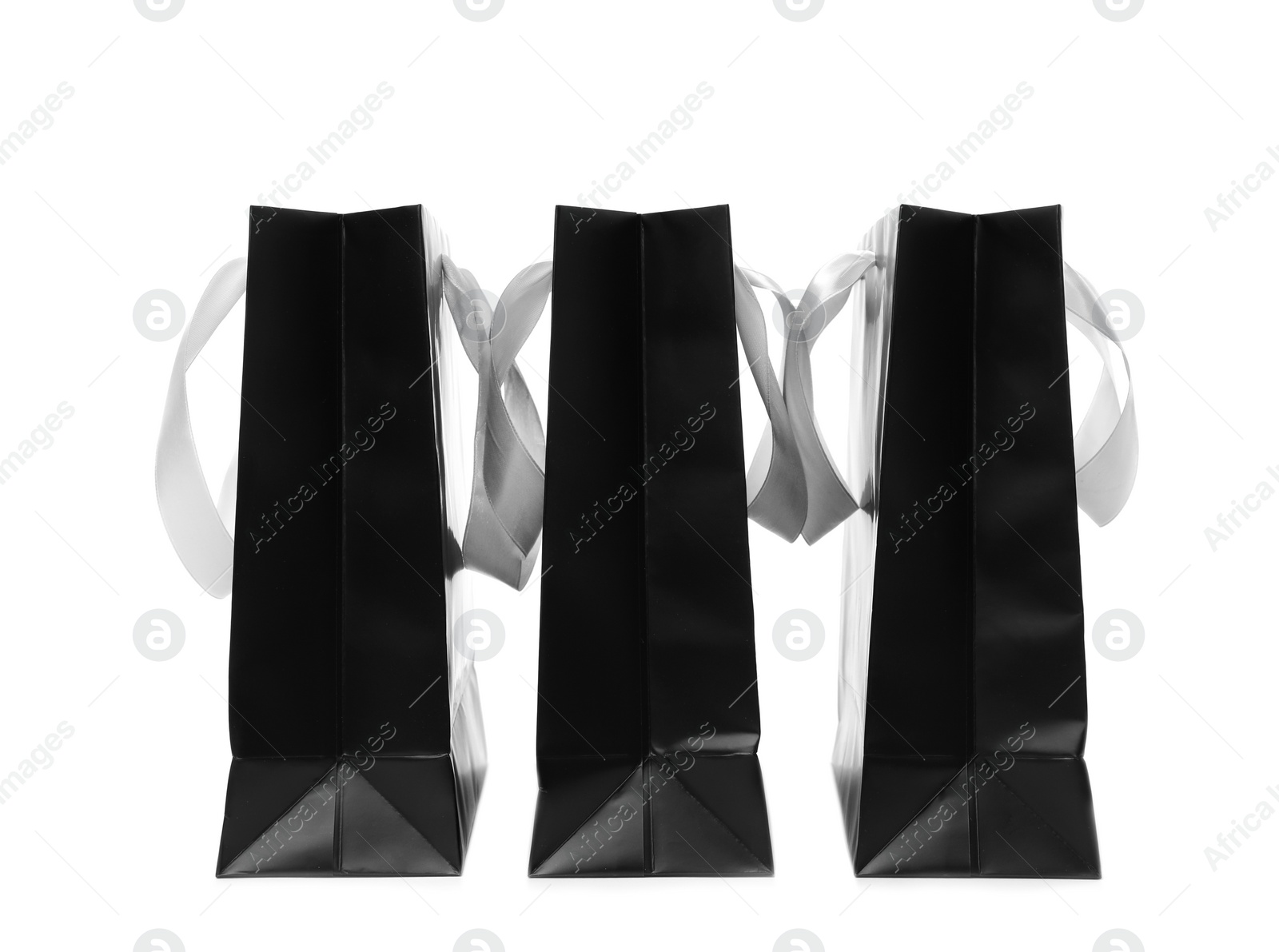 Photo of Paper shopping bags with ribbon handles on white background