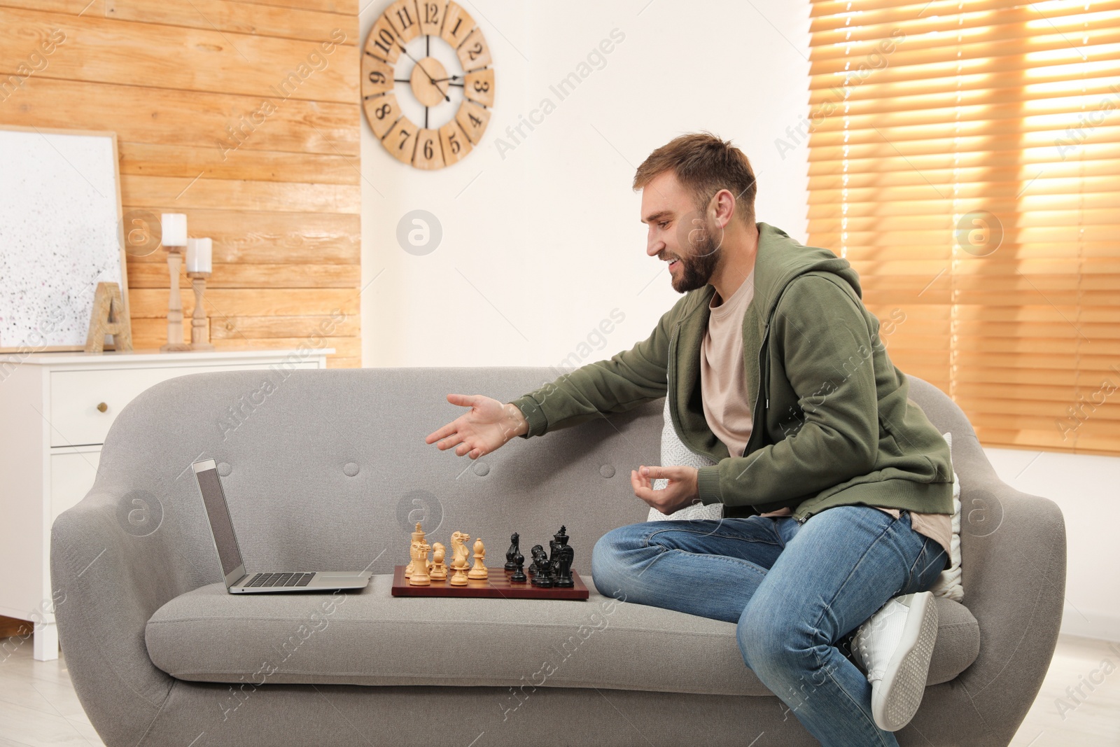 Photo of Young man playing chess with partner through online video chat in living room