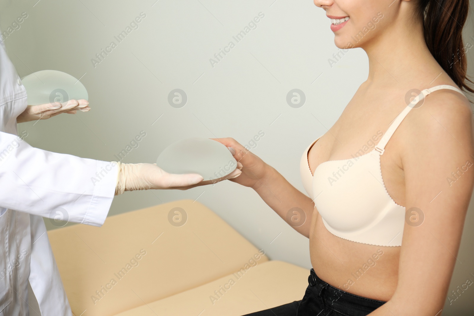 Photo of Doctor showing silicone implants for breast augmentation to patient in clinic, closeup. Cosmetic surgery