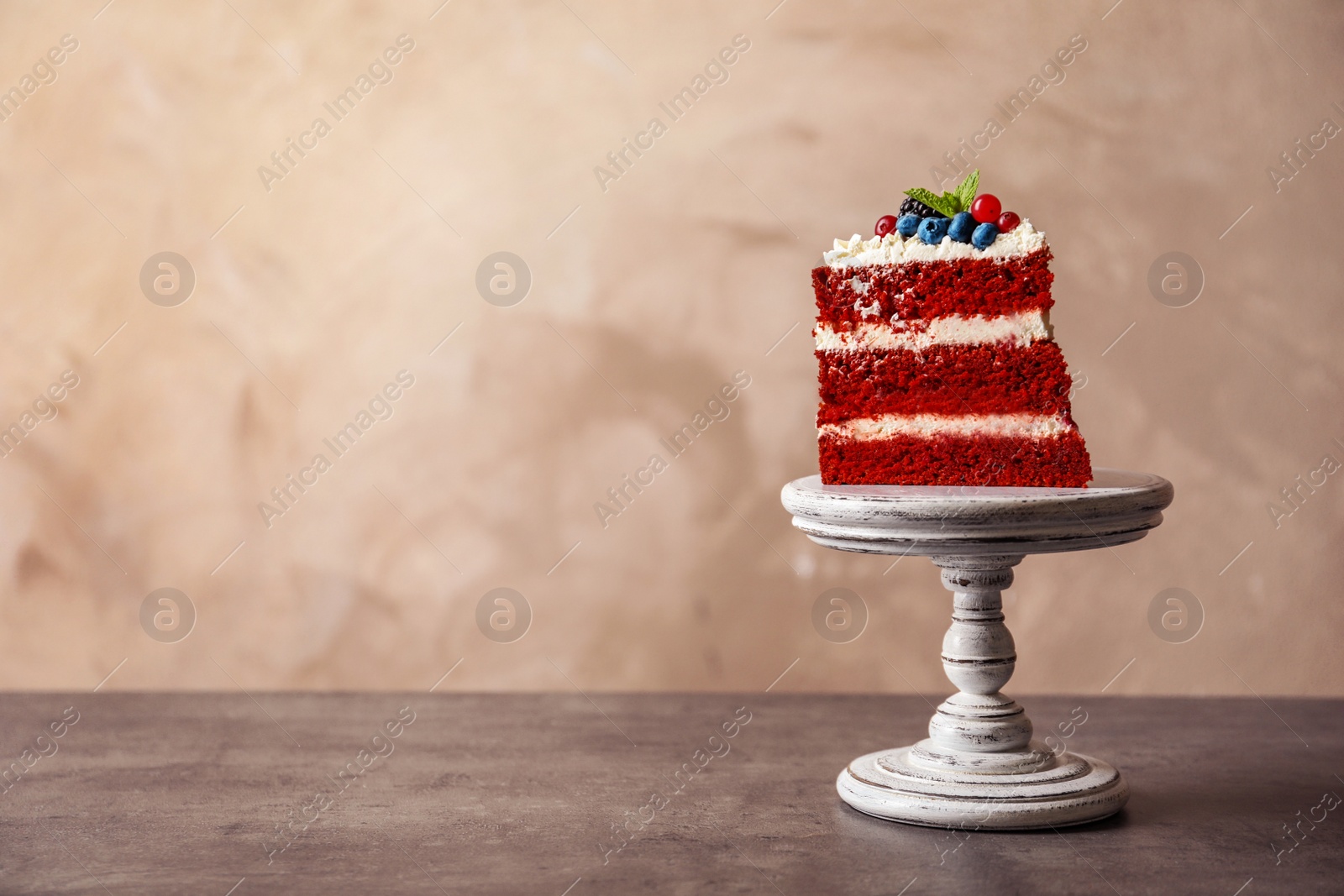 Photo of Stand with piece of delicious homemade red velvet cake and space for text on color background