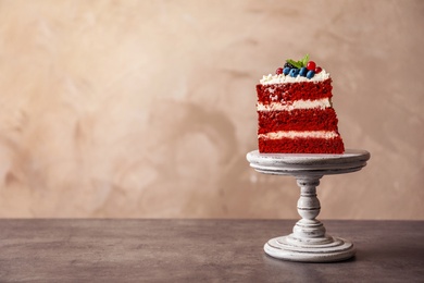 Stand with piece of delicious homemade red velvet cake and space for text on color background