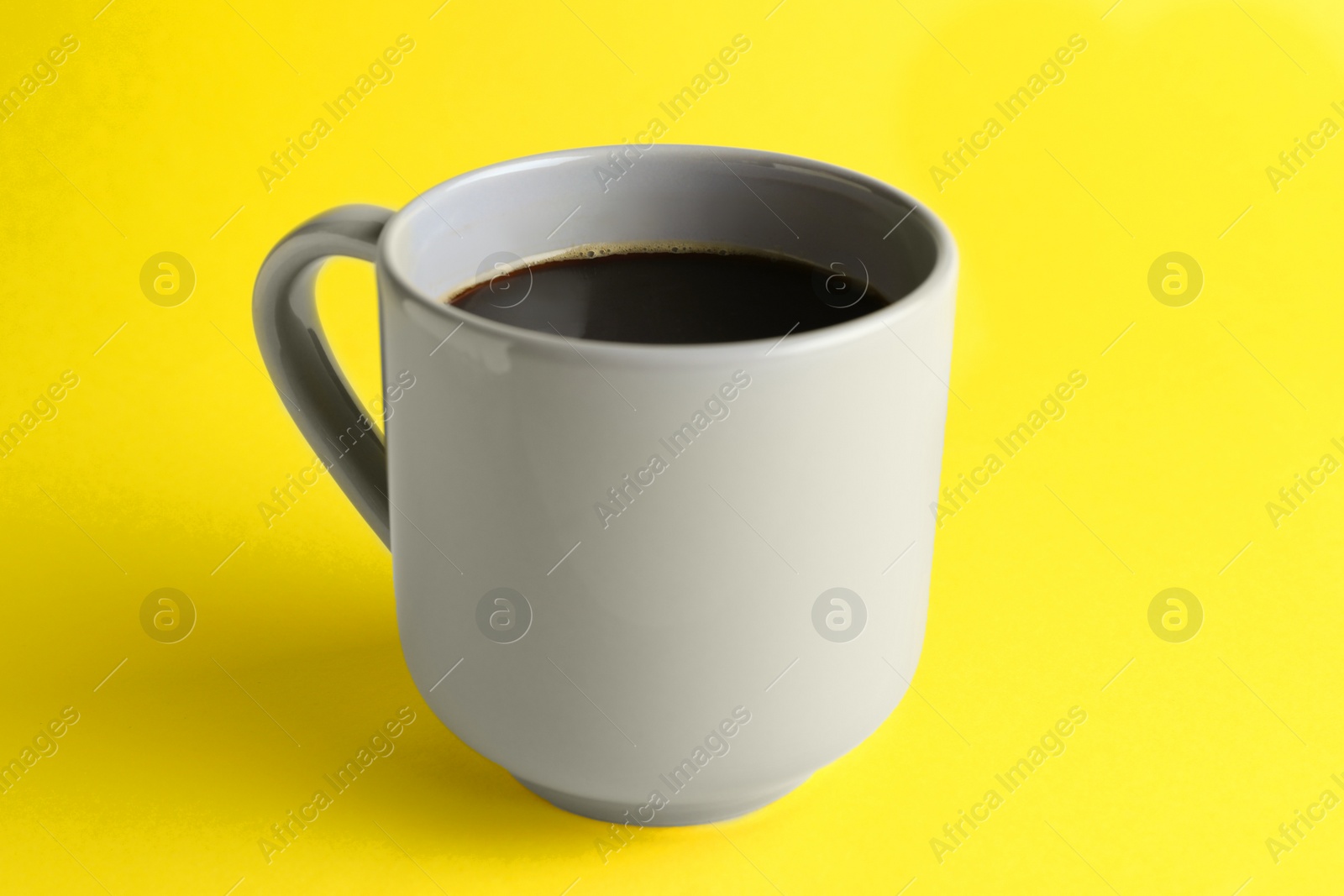 Photo of Grey mug of freshly brewed hot coffee on yellow background