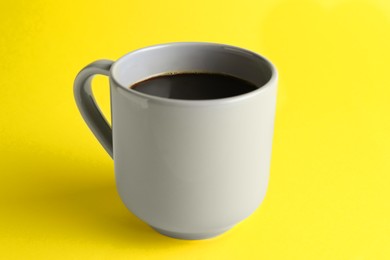 Photo of Grey mug of freshly brewed hot coffee on yellow background
